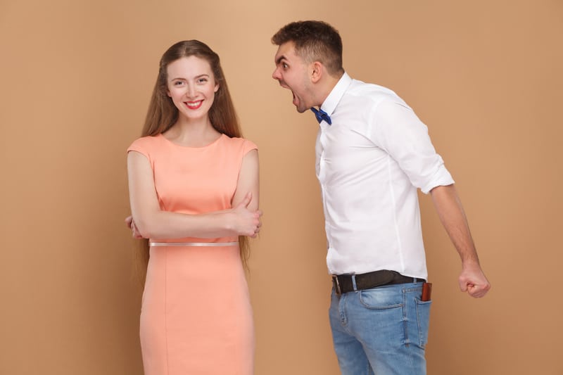 Crazy young man in white shirt standing and screaming at woman i