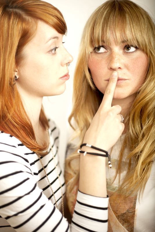 red haired and blond girl sign to shut up