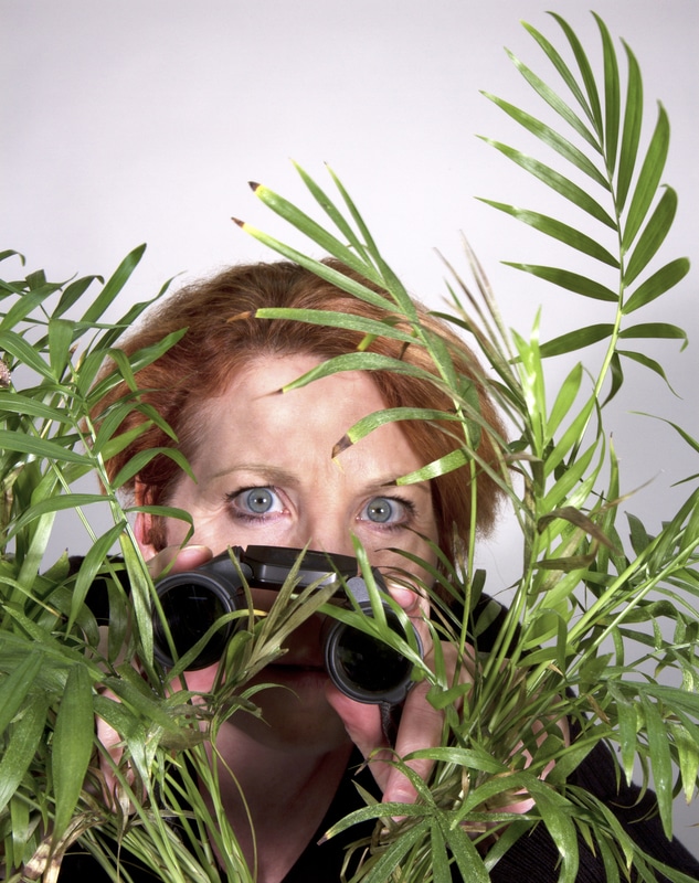 Woman looking through plant with binoculars