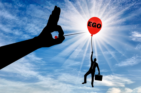 A selfish businessman clings to a balloon called the ego and a big hand with a needle intends to burst it