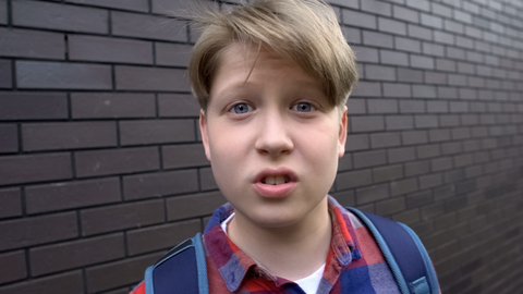 Bully boy teasing into camera, expressing aggression, POV victim of bullying
