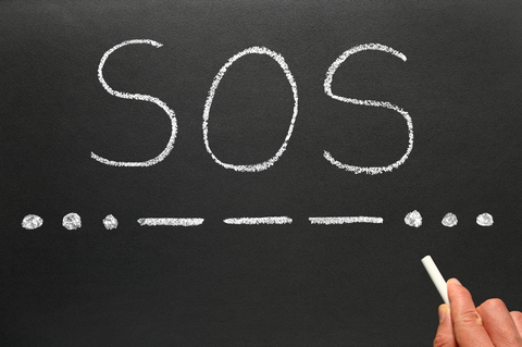 SOS the international Morse Code distress signal written on a blackboard.