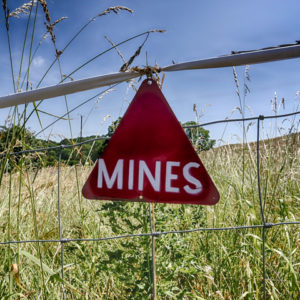 Fenced off field with sign on fence warning of mines