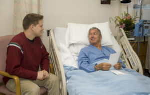 Younger man visiting older man in a hospital or elder care facility