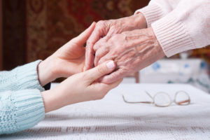 Younger hands holding elderly hands in support