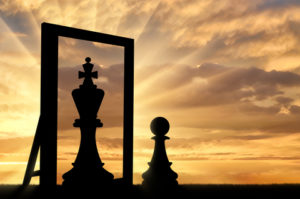 confidence, empowerment, smaller chess piece looking in the mirror to see bigger chess piece
